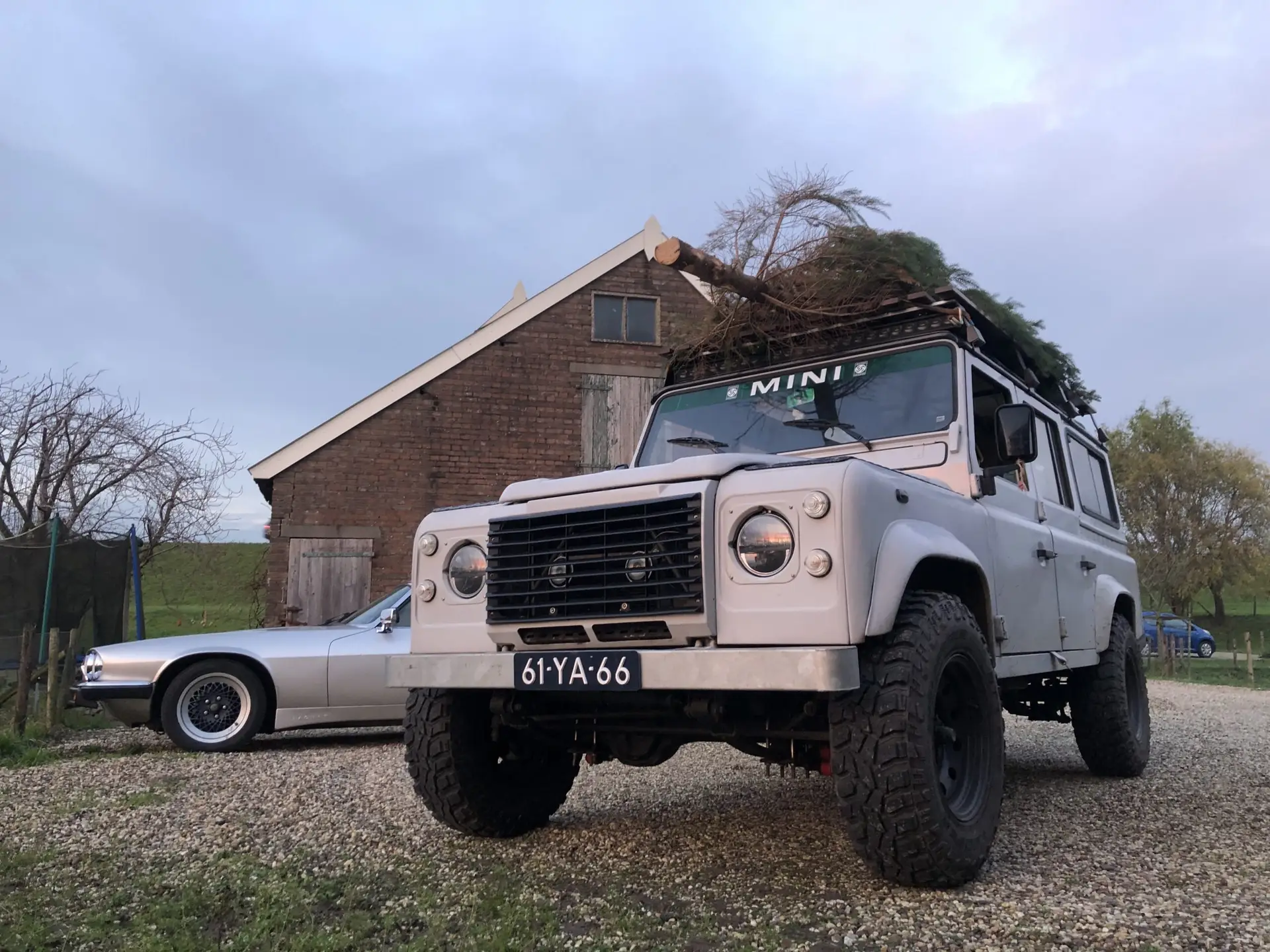 In the front the Brooks company car, a white Land Rover. In the back a side image of the front of a Jaguar XJS V12 is shown