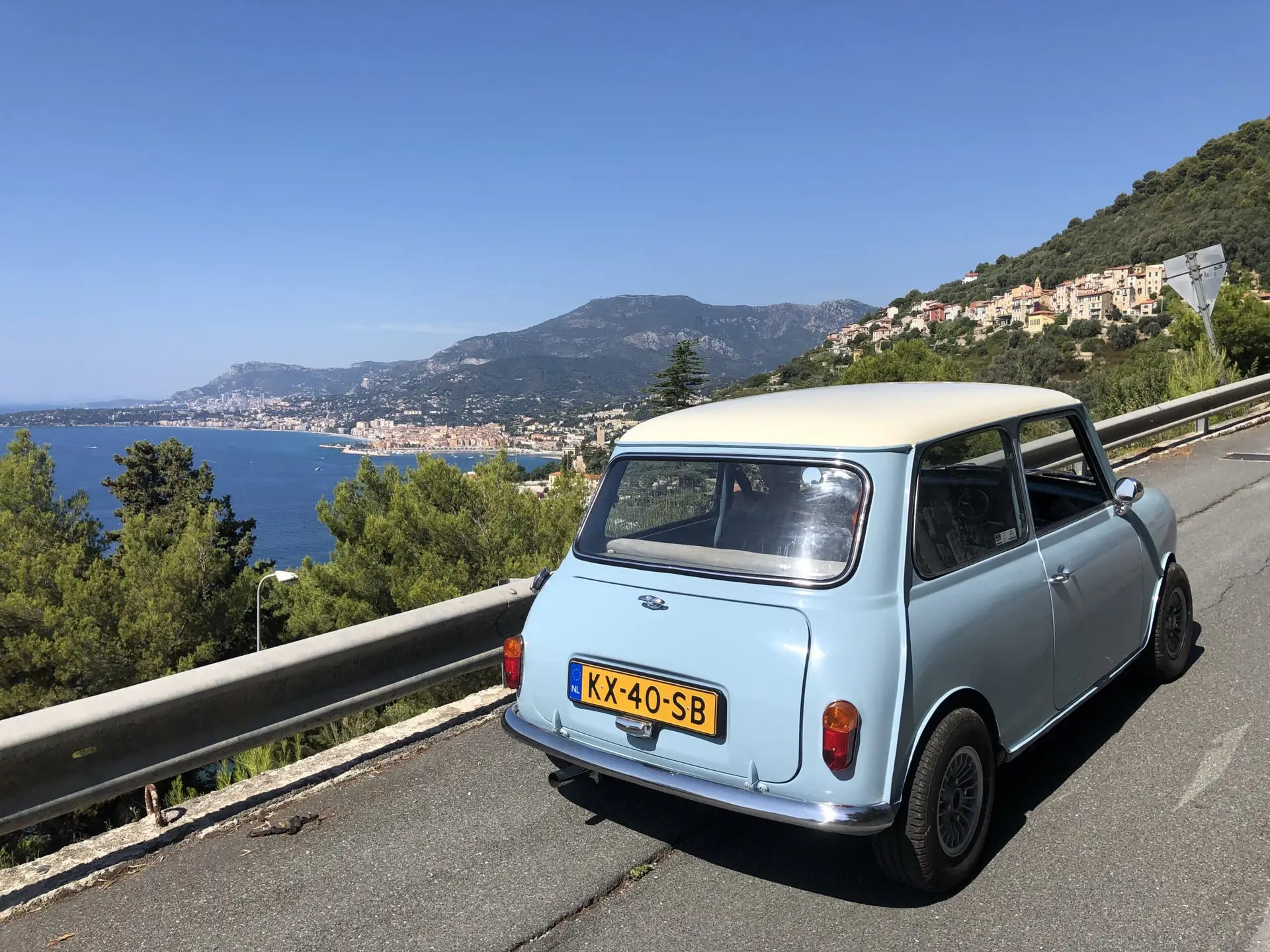 A light blue Austin Mini driving through the mountains