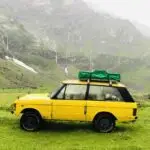 A yellow Range Rover Suffix C with on the background beautiful mountains.