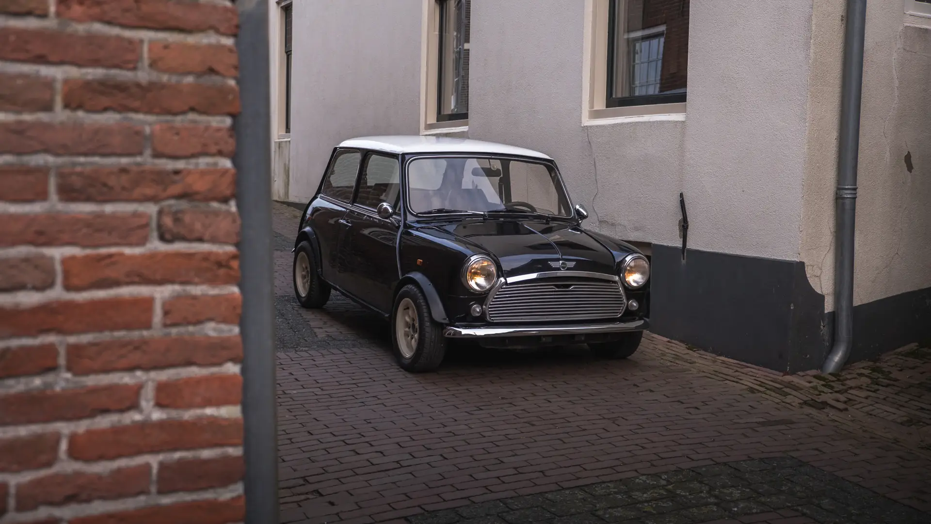 A black Mini City driving out of the alley