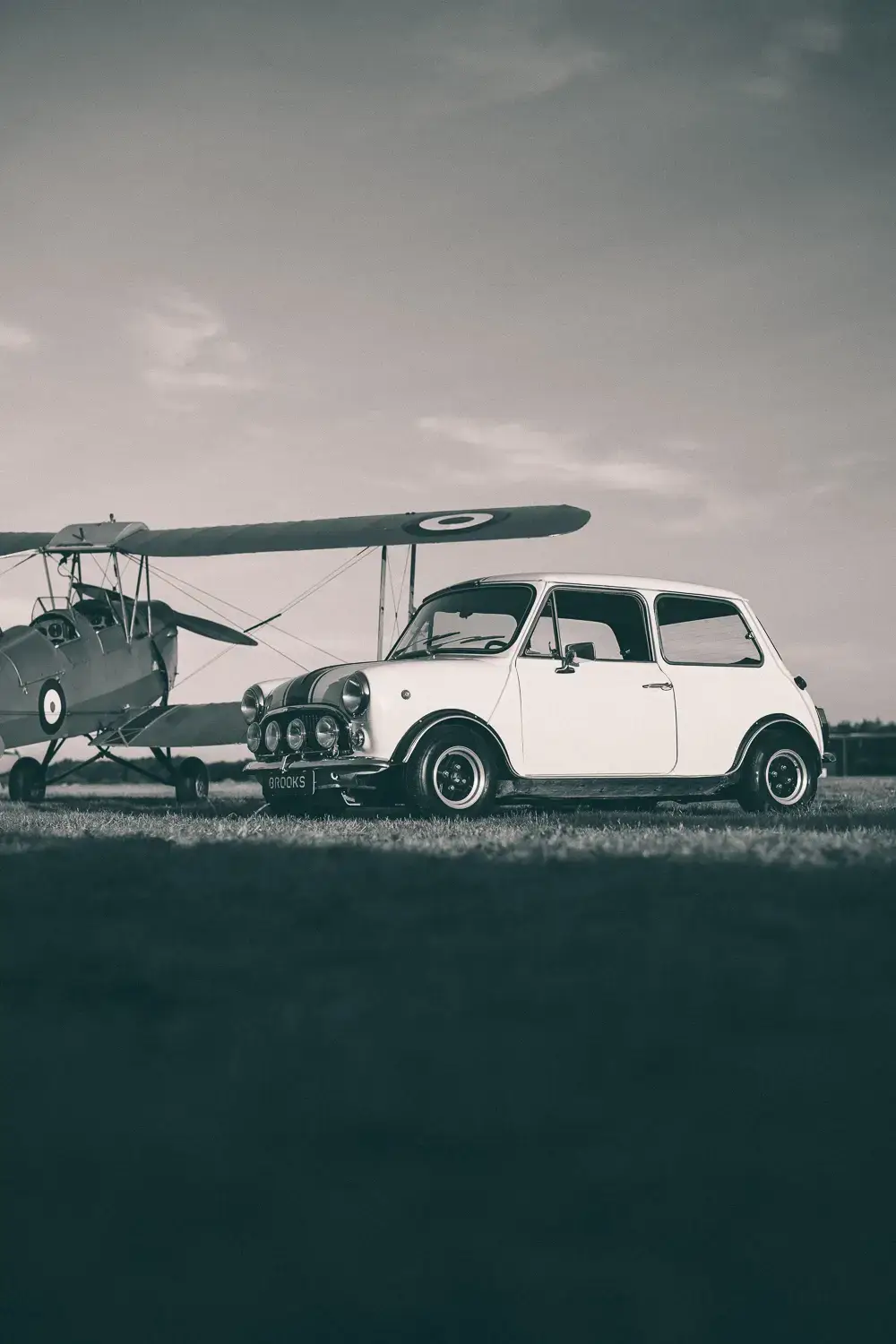 black and white picture of a Brooks Mini classic standing next to an airplane