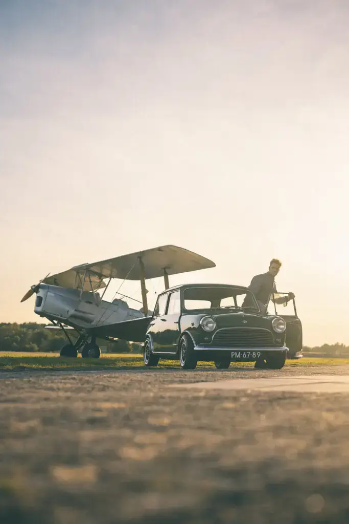 green mini classic MK1 with a Tiger Moth airplane in the back