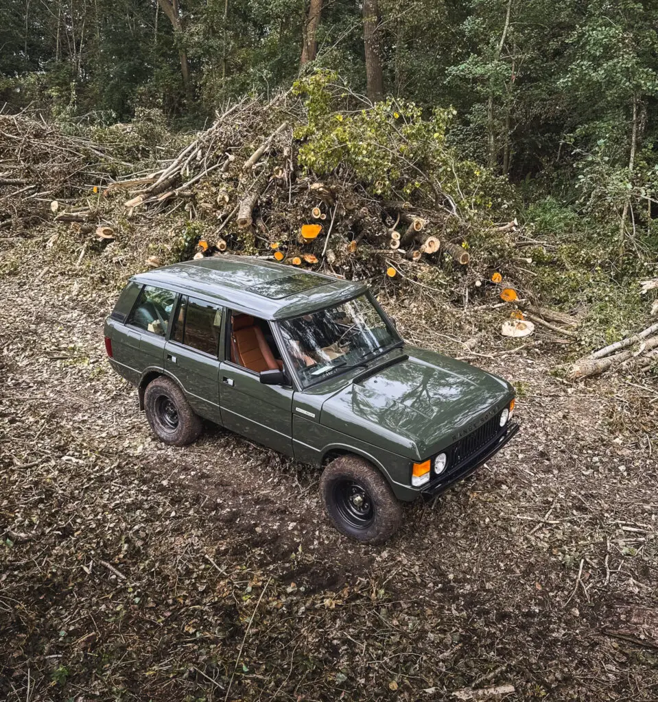 land rover range rover classic dark green in the woods with black steel rims